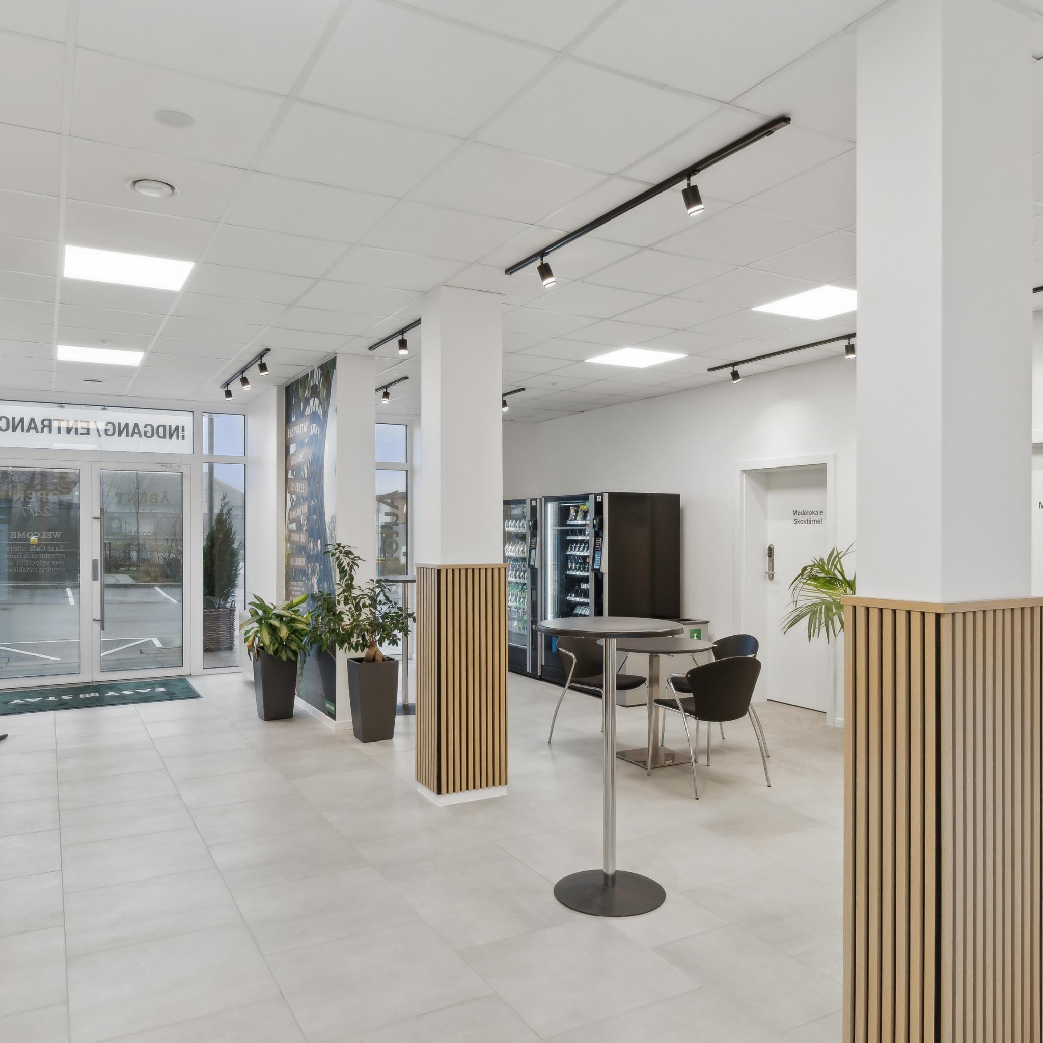 Lyst fællesområde i lobbyen på Easy Stay Hotel Rønnede med siddepladser og automater.