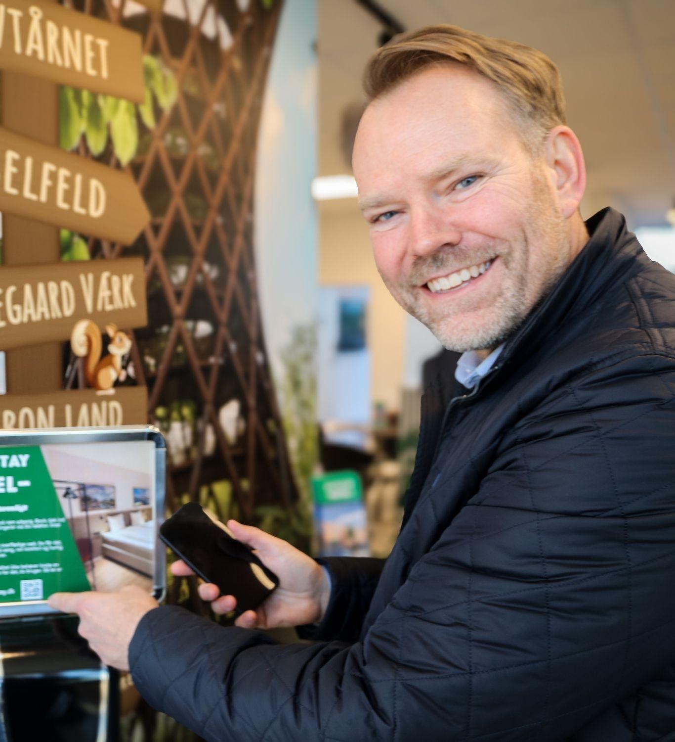 Dennis Dahl kan kontaktes om Easy Stay, han peger på Easy Stay logo og check in med mobil